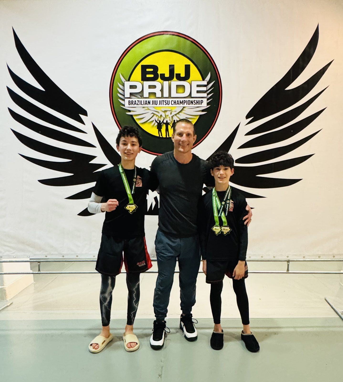 Coach Jay with two students wearing gold medals at BJJ Pride