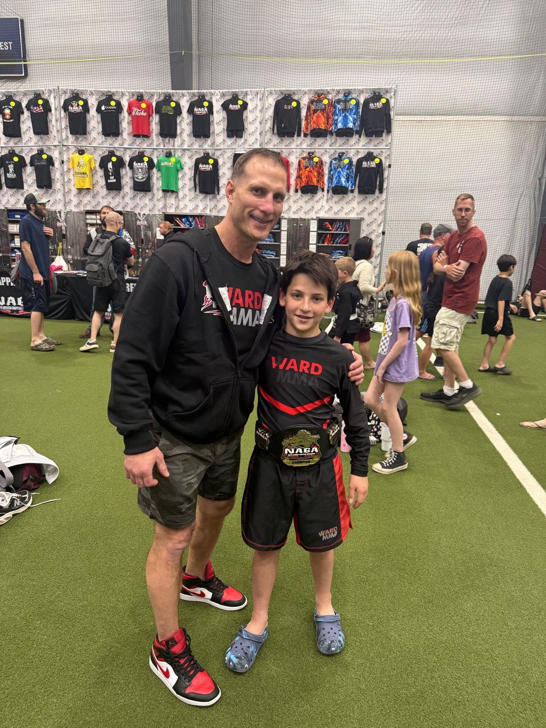 Coach Jay with a young student wearing a NAGA champion belt