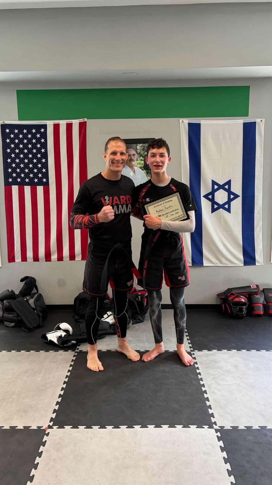 Coach Jay with a student holding a promotion certificate