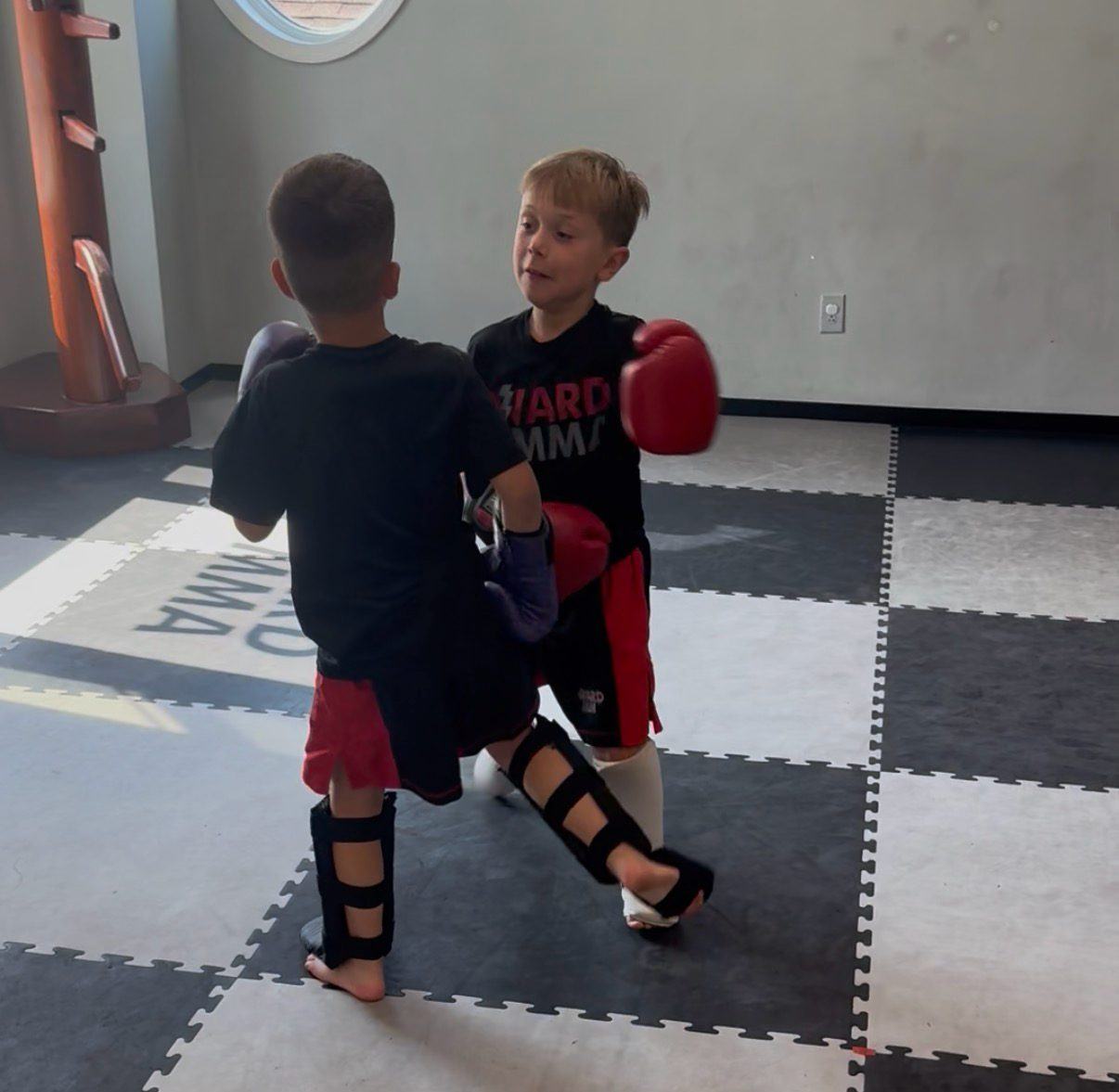 Two young students sparring in gloves and shin guards