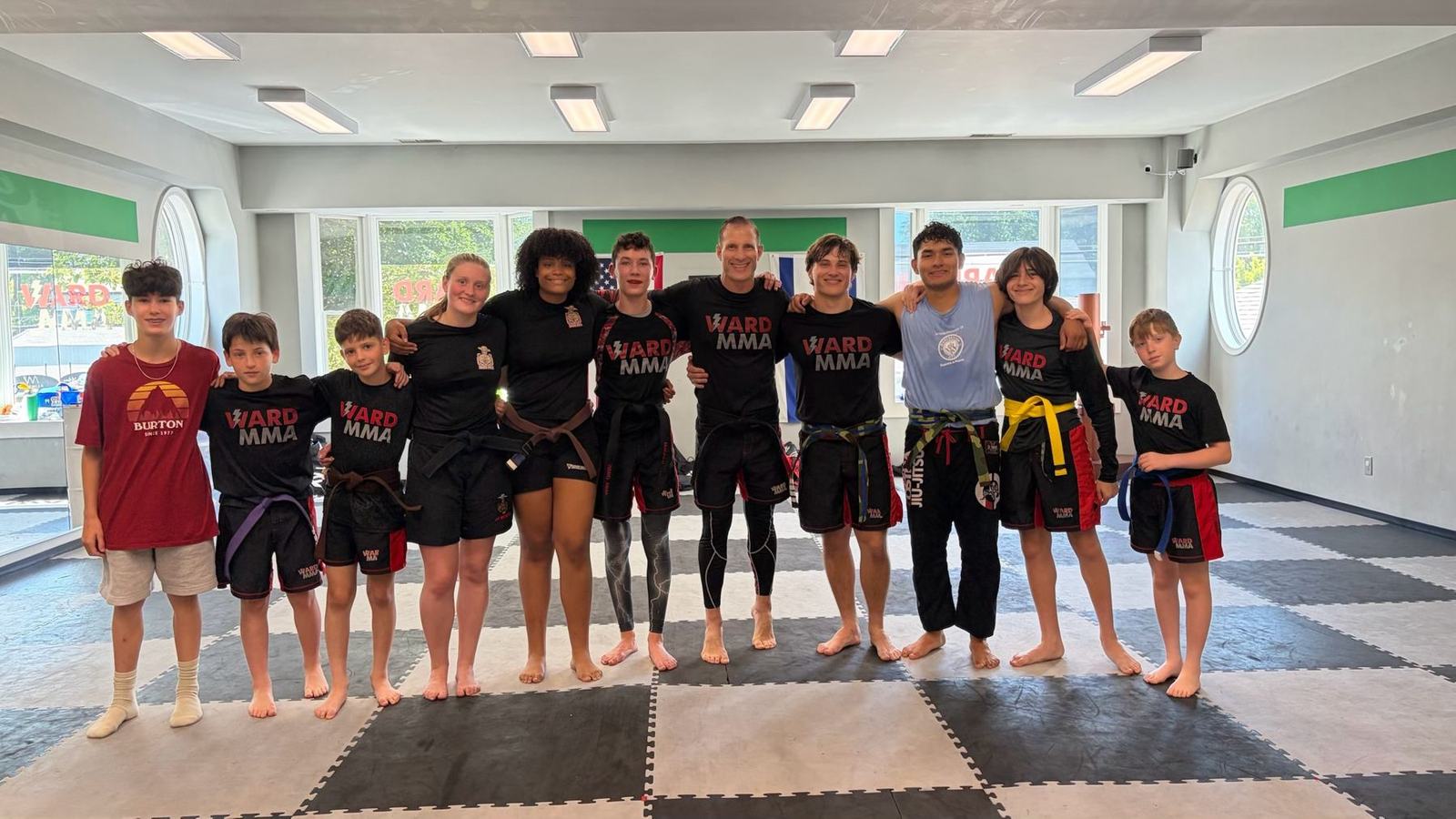 Coach Jay with a row of Ward MMA students in team shirts and belts